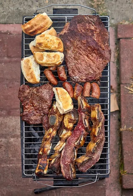 Parrilla vista de arriba con bife, chorizos, asado y pan